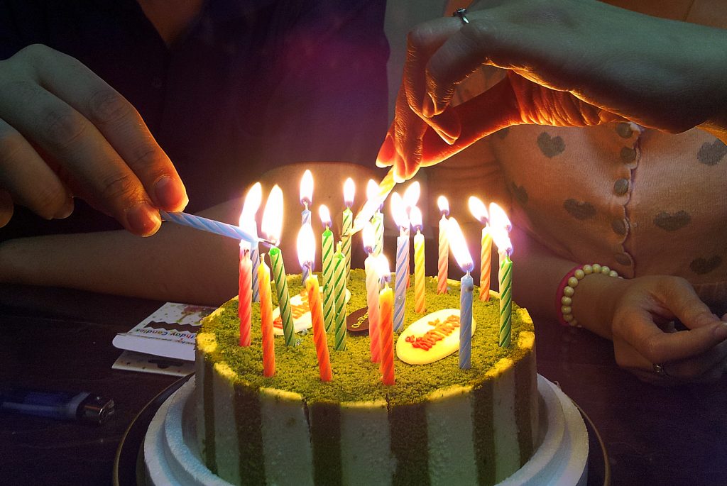 Photo of a Birthday Cake lighten up together by a family in dark light