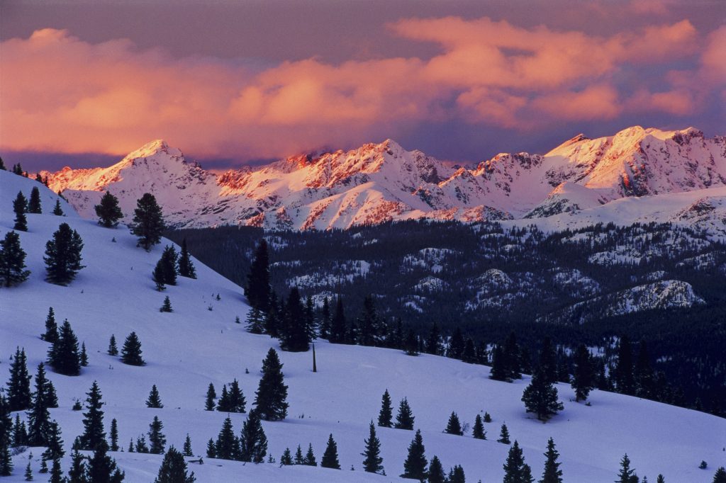 Gore Range in Winter during winter solstice sunset with pink and orange dramatic alpenglow. Scenic landscape with fresh snow with rugged jagged peaks lit up with pink light. Also crops well for amazing pano image too. Captured on film and drum scanned from vibrant transparency film.