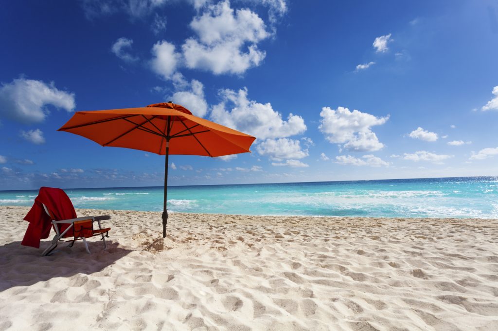 Beautiful orange umbrella and chair on the white sand beach